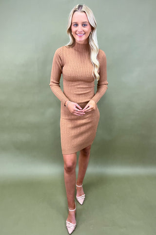 Woman wearing a brown ribbed dress against a green background