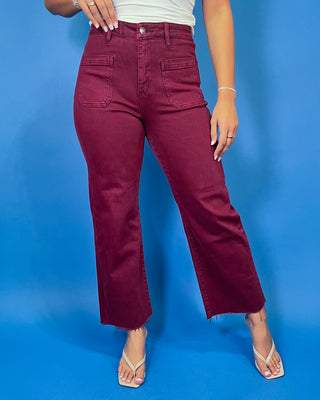 Burgundy high-rise cropped straight leg jeans with front patch pockets and a trendy raw hem.