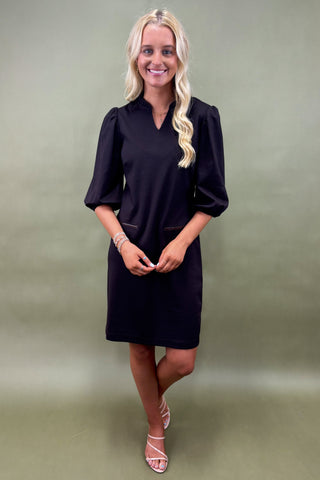 Woman wearing a black dress against a green background