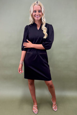 Woman wearing a black dress against a green background