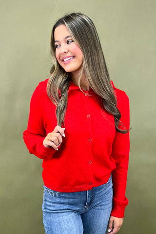 Woman wearing a red shirt and blue jeans against a green background