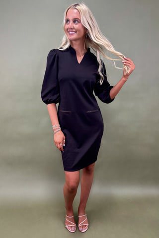 Woman wearing a black dress against a plain background