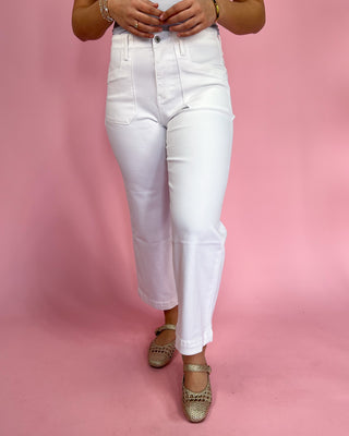 Person wearing white jeans on a pink background