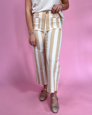 Person wearing beige and white striped pants on a pink background