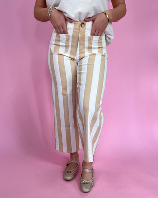 Person wearing beige and white striped pants on a pink background