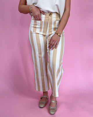 Person wearing beige and white striped pants on a pink background
