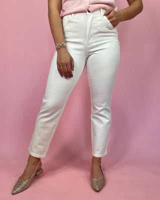 Person wearing white jeans and a pink top on a pink background