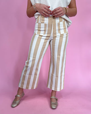 Person wearing beige and white striped pants on a pink background