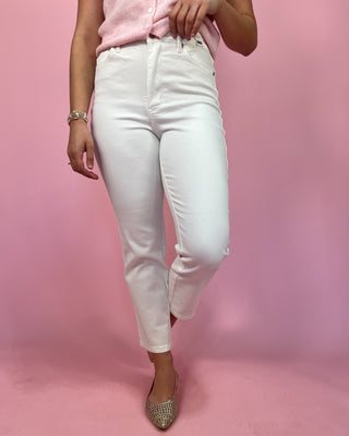 Person wearing white jeans and a pink top on a pink background