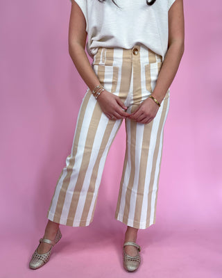 Person wearing beige and white striped pants on a pink background