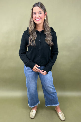 Woman wearing a black shirt and blue jeans against a green background