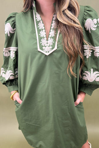 Green dress with white embroidery on a plain background