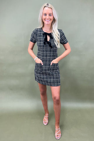 Woman wearing a black and white checkered dress against a plain background