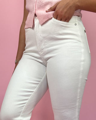 White jeans worn by a person against a pink background