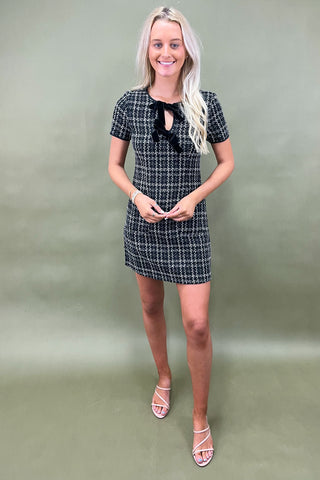 Woman wearing a black and white checkered dress against a plain background