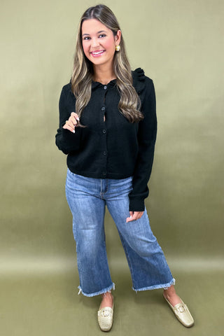 Woman wearing a black shirt and blue jeans against a gold background