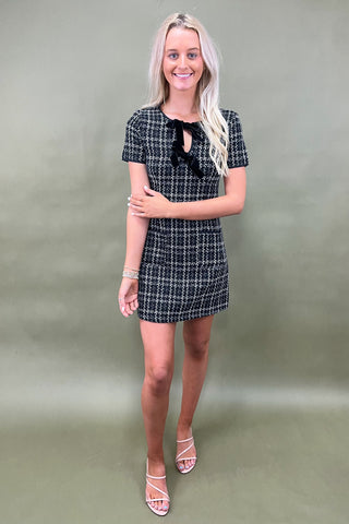 Woman wearing a black and white checkered dress against a plain background