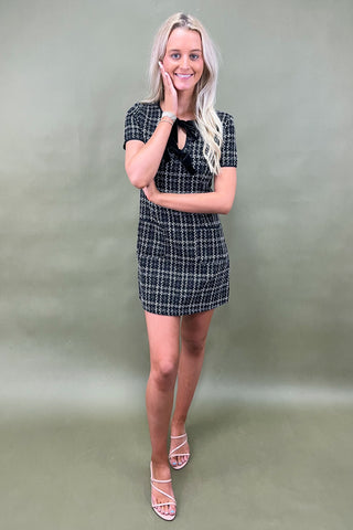 Woman wearing a black and white checkered dress against a plain background