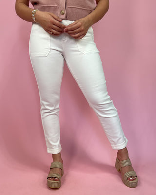 Person wearing white jeans and a pink top on a pink background