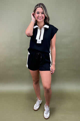 Woman wearing a black and white outfit with a plain background