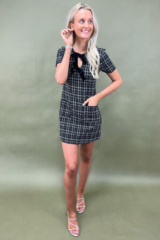 Woman wearing a black and white checkered dress against a plain background