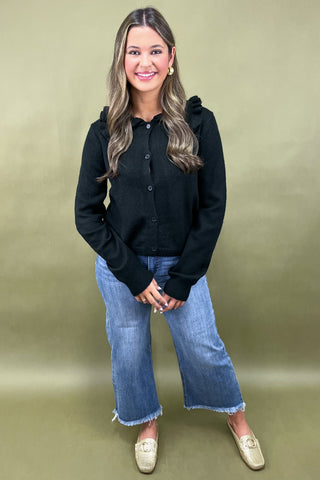 Woman wearing a black shirt and blue jeans against a green background