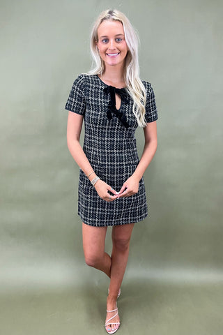 Woman wearing a black and white checkered dress against a plain background