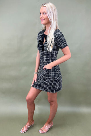 Woman wearing a black and white checkered dress against a plain background