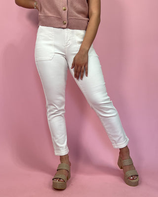 Person wearing white jeans and a pink cardigan on a pink background