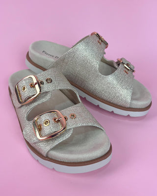 Gold glitter double-buckle slide sandal with cushioned footbed on pink background