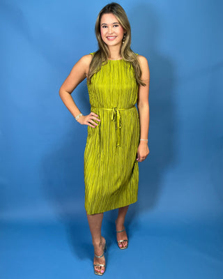 A woman modeling a sleeveless olive green pleated midi dress with a tie waist