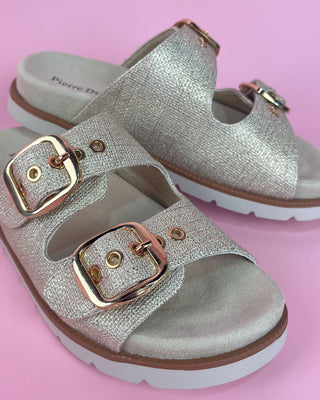 Gold glitter double-buckle slide sandal with cushioned footbed on pink background