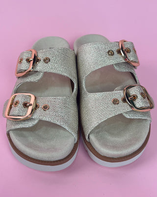 Gold glitter double-buckle slide sandal with cushioned footbed on pink background