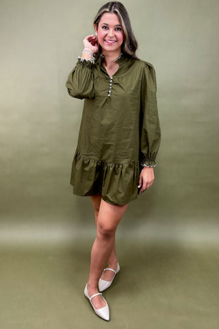Woman wearing an olive green dress with a plain background