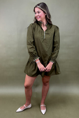 Woman wearing an olive green dress with a plain background