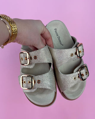 Gold glitter double-buckle slide sandal with cushioned footbed on pink background