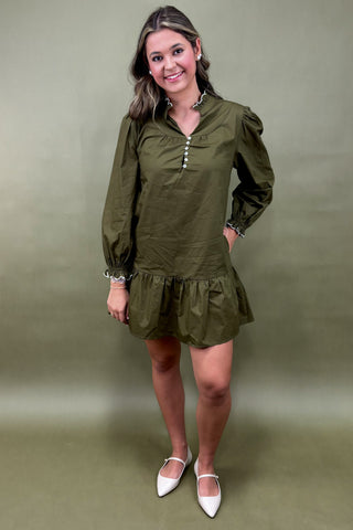 Woman wearing an olive green dress with a plain background