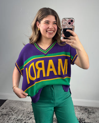 Person wearing a colorful sweater with 'MARDI' text, taking a selfie.