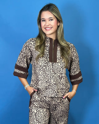A woman modeling a matching two-piece leopard print lounge set with brown trim