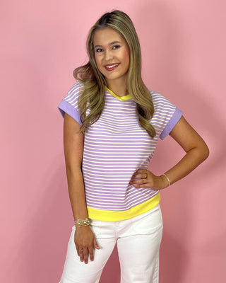 Woman wearing a striped shirt with purple and yellow colors on a pink background