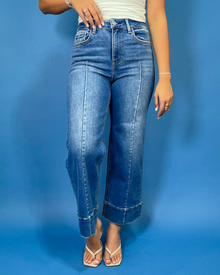 Medium wash high-rise cropped wide leg jeans with front seam detailing, subtle fading, a wide cuffed hem, and small front hem slits.
