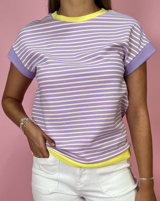 Person wearing a purple and white striped shirt with yellow trim on a pink background