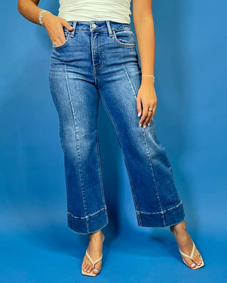 Medium wash high-rise cropped wide leg jeans with front seam detailing, subtle fading, a wide cuffed hem, and small front hem slits.