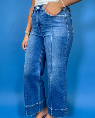 Medium wash high-rise cropped wide leg jeans with front seam detailing, subtle fading, a wide cuffed hem, and small front hem slits.