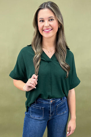 Woman wearing a green top and blue jeans against a green background