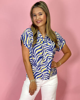 Woman wearing a blue and yellow patterned shirt against a pink background
