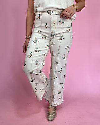 Person wearing white pants with duck pattern on a pink background
