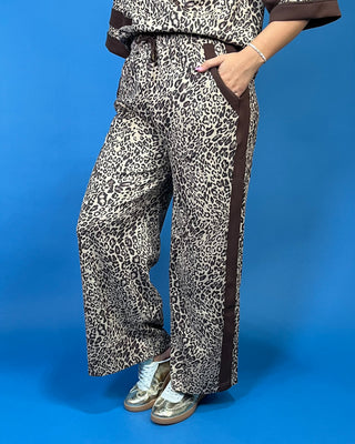 A person wearing wide-leg leopard-print pants with dark brown side panels and a matching top