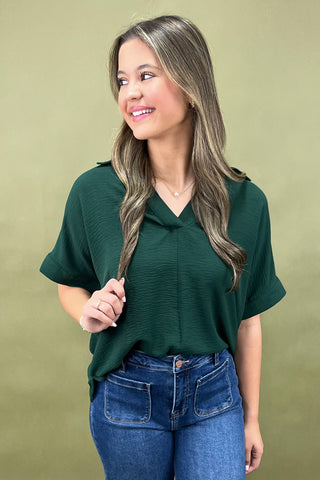 Woman wearing a green top and blue jeans against a green background