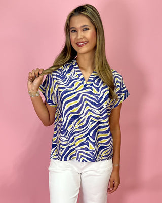 Woman wearing a blue and yellow patterned blouse against a pink background